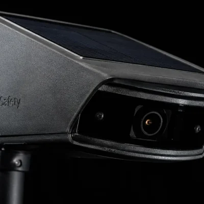 Macro photograph of a solar-powered Flock Safety automatic license plate reader camera against a black background