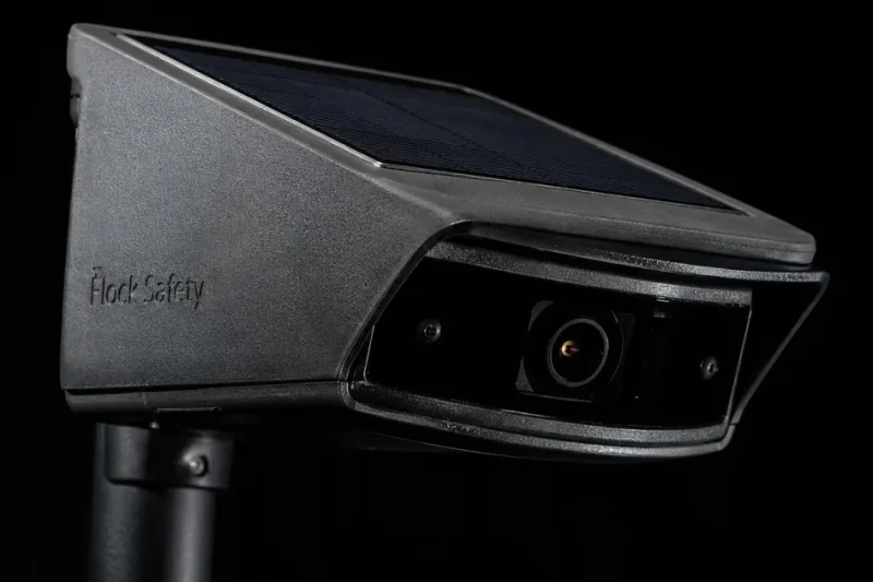 Macro photograph of a solar-powered Flock Safety automatic license plate reader camera against a black background