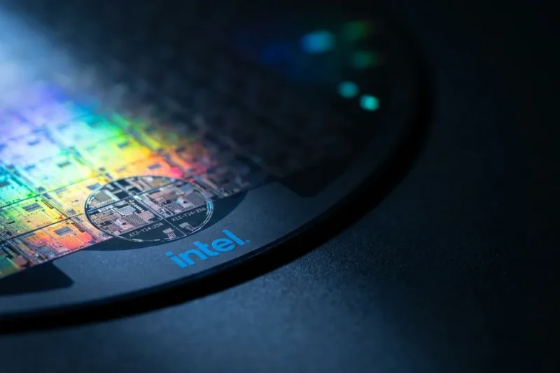 Extreme macro of a silicon semiconductor wafer showing iridescent die grid, with the Intel logo printed on the dark wafer carrier frame