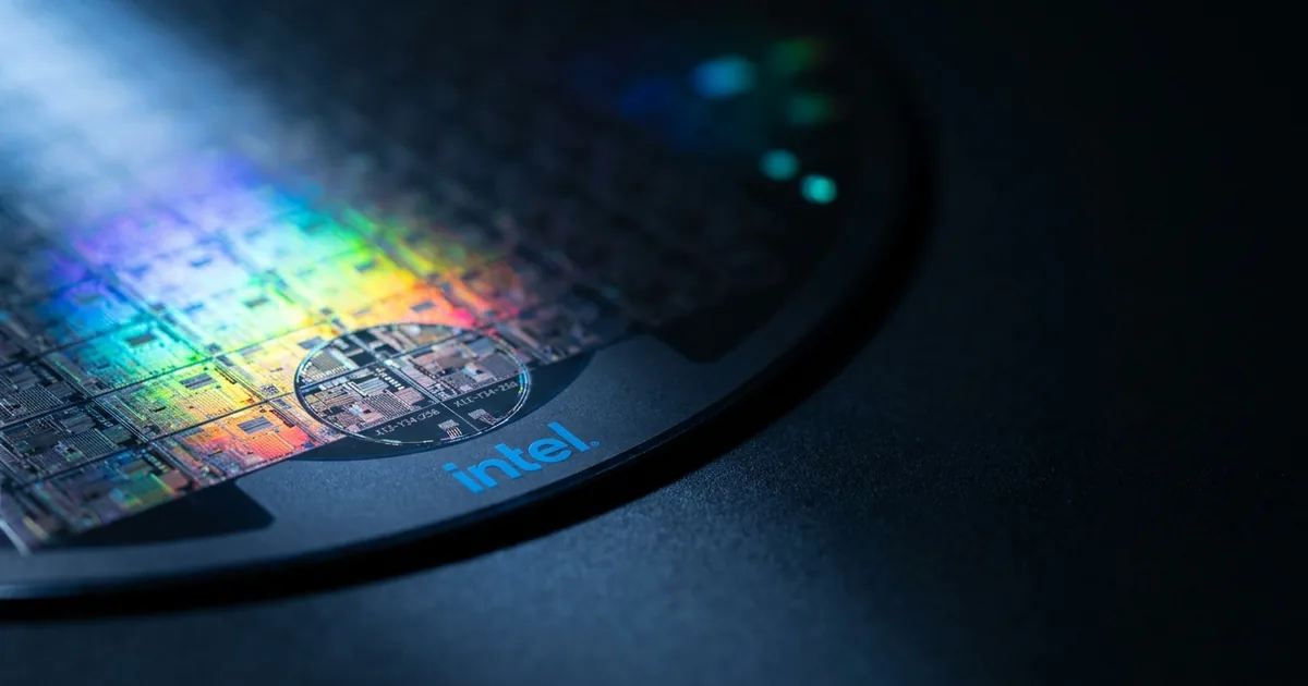 Extreme macro of a silicon semiconductor wafer showing iridescent die grid, with the Intel logo printed on the dark wafer carrier frame